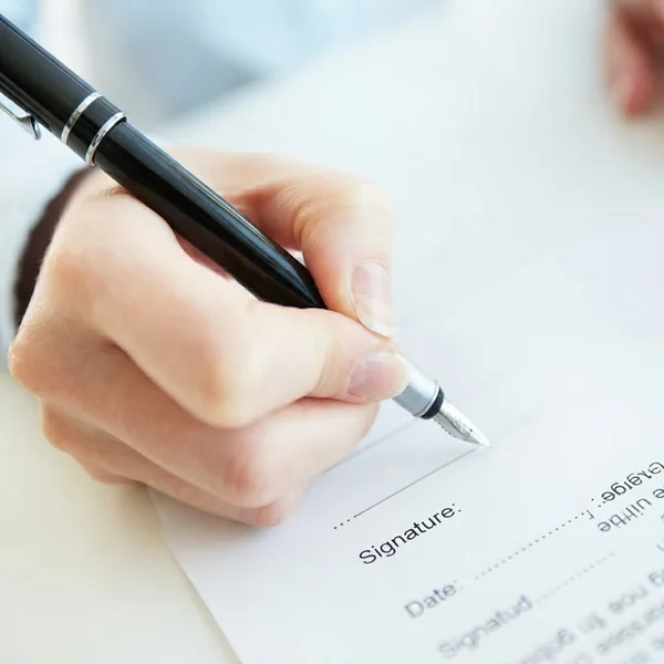 Hand die met een vulpen een document ondertekent bij het vakje Signature