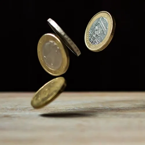 Drie euromunten die op een houten tafel vallen